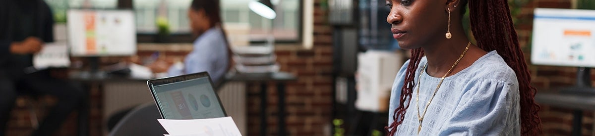 Una mujer sentada en la mesa de una oficina, revisando papeleo